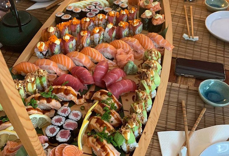An exquisite and full boat of different kinds of sushi and sashimi