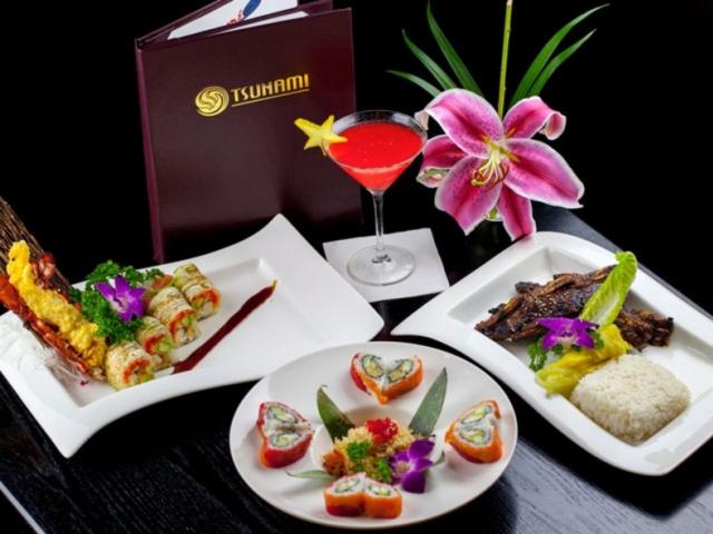 A table filled with three separate types of plates and a house cocktail, offered at Tsunami Sushi and Hibachi Grill