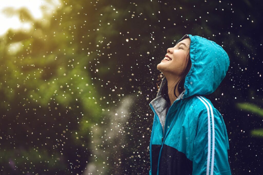 A woman standing under the rain and smiling
