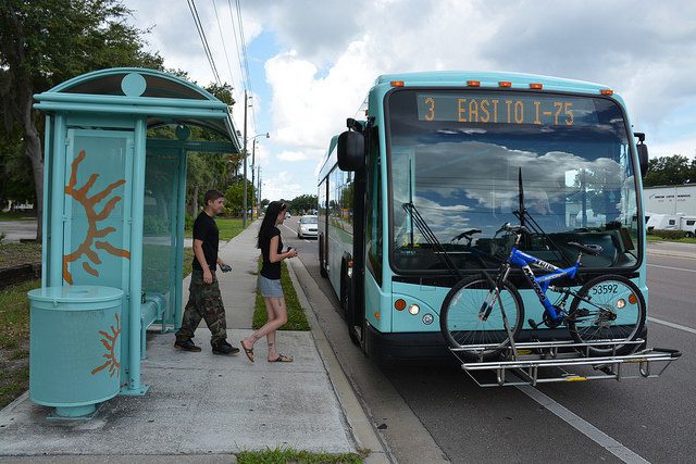 A young man and woman mounting the Anna Maria Island Trolley, which has a bike loaded at its front.
