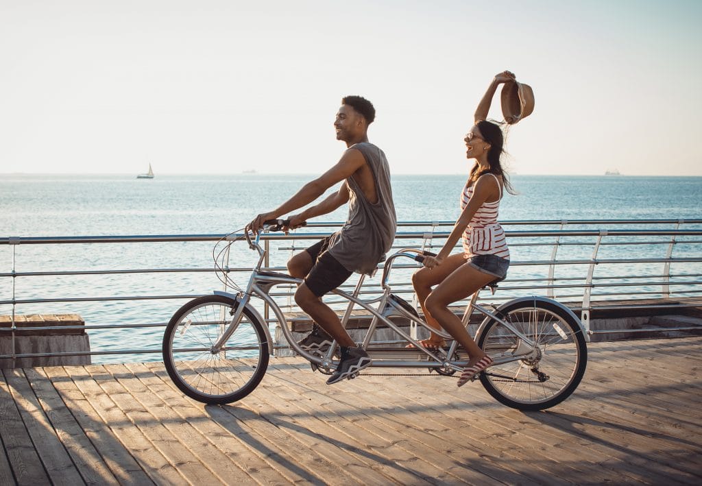 A young couple enjoying a romantic ride on a tandem bike, cruising along the Anna Maria Island Pier.