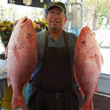 Captain Anthony Manali, holding 2 red snappers in hand - his fresh catch of the day.