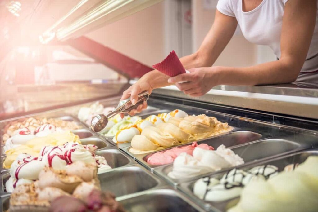 A woman filling an ice cream cone.